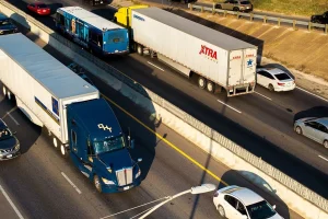 A highway scene featuring a commercial semi-truck and passenger vehicles side by side