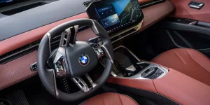 A close-up view of a modern BMW interior showing a large digital touchscreen dashboard instead of traditional physical