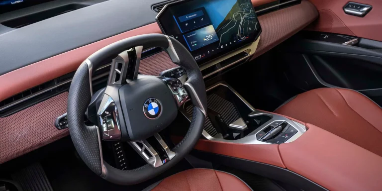 A close-up view of a modern BMW interior showing a large digital touchscreen dashboard instead of traditional physical