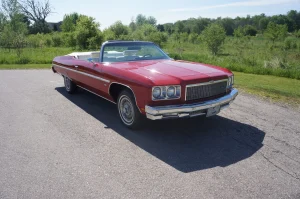 A red 1975 Chevrolet Caprice Classic Convertible with a white folding roof parked outside