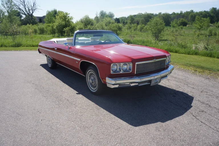 A red 1975 Chevrolet Caprice Classic Convertible with a white folding roof parked outside