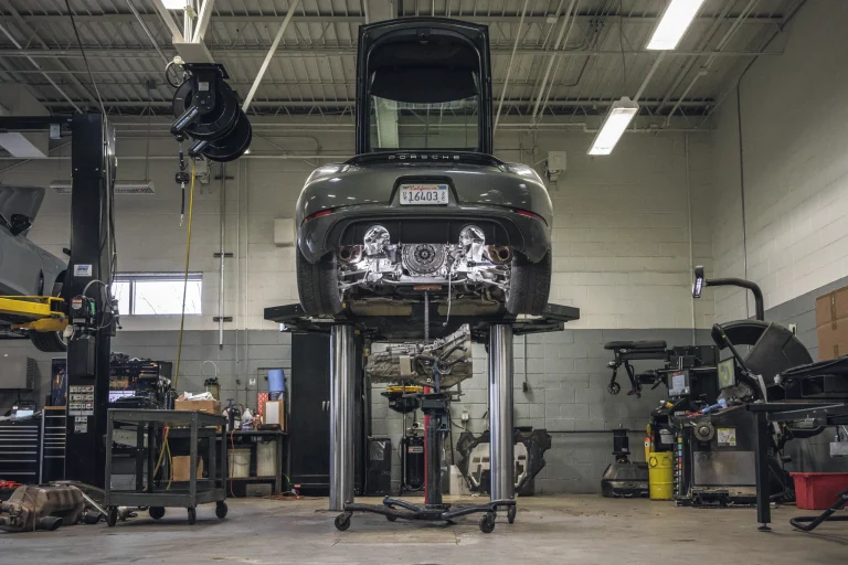 Mechanic performing routine maintenance on a modern vehicle in a professional workshop.