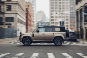 A modern Land Rover Defender driving on a rugged off-road trail.