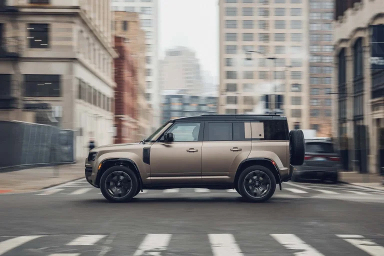 A modern Land Rover Defender driving on a rugged off-road trail.