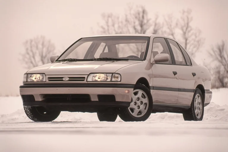 A silver 1991 Infiniti G20 luxury sedan parked on a scenic road, highlighting its aerodynamic design and compact dimensions.