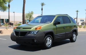 A well-preserved silver 2001 Pontiac Aztek with its camping tent accessory pitched at the rear.