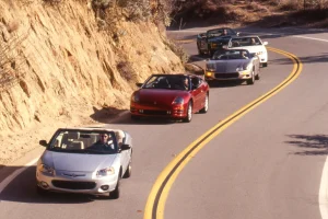Vintage 2001 four-seat convertible cars lined up for a professional comparison test photo session.