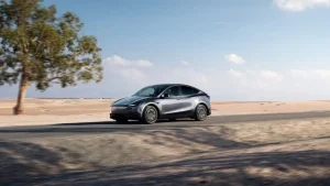 A modern Tesla Model Y vehicle parked on a highway shoulder