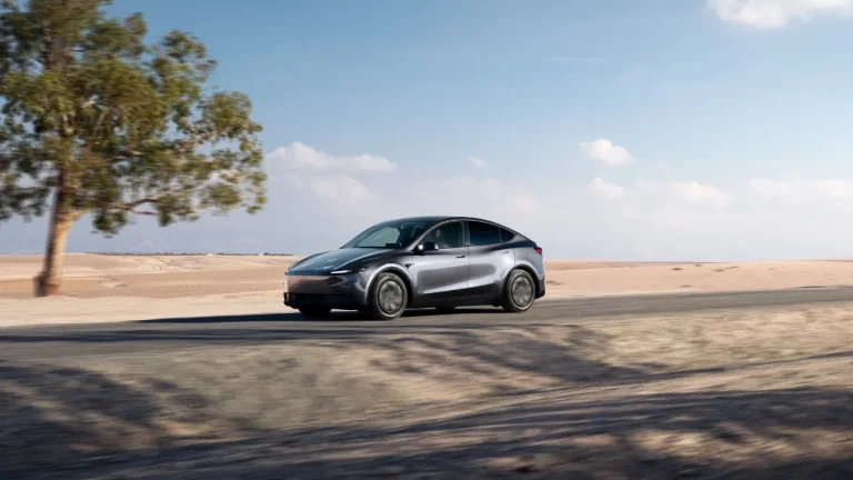 A modern Tesla Model Y vehicle parked on a highway shoulder