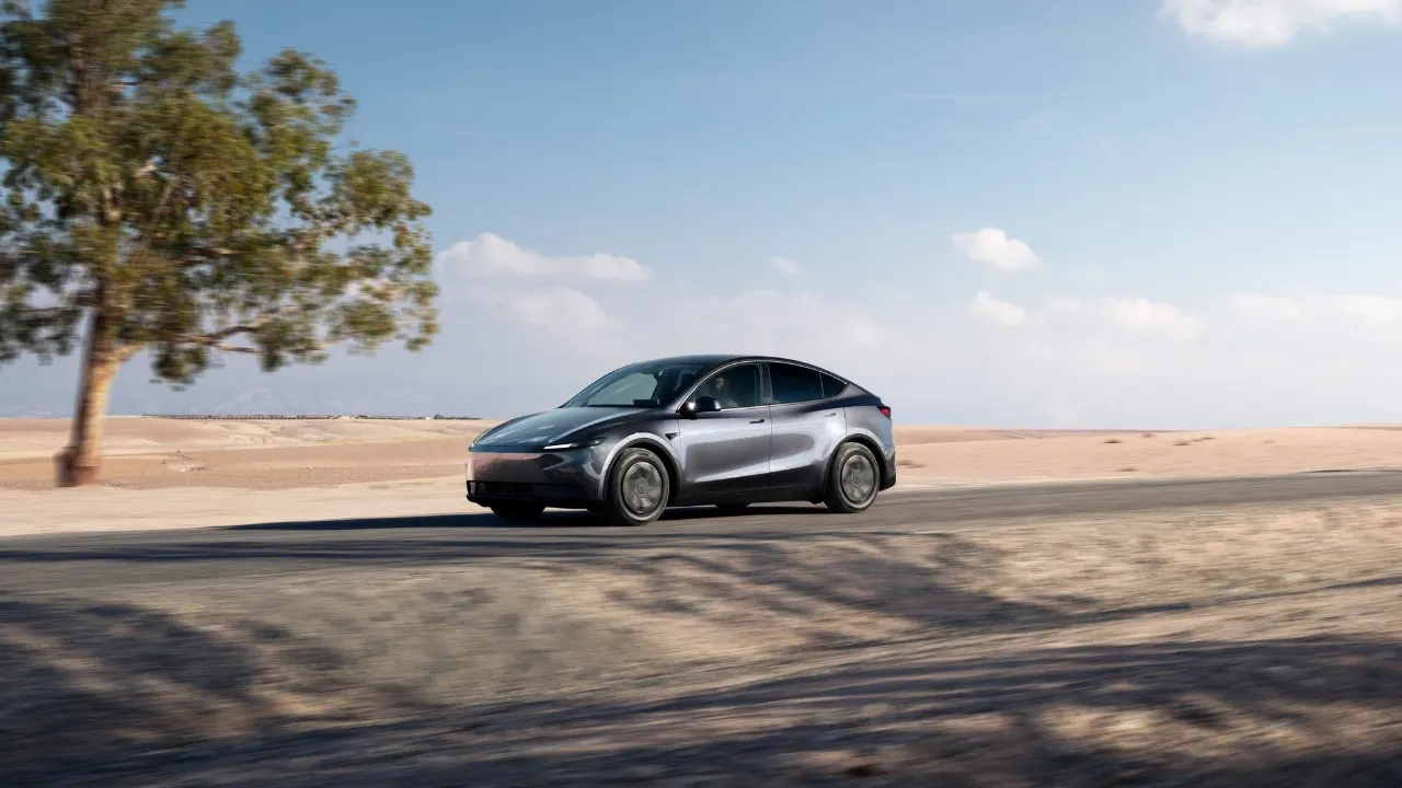 A modern Tesla Model Y vehicle parked on a highway shoulder