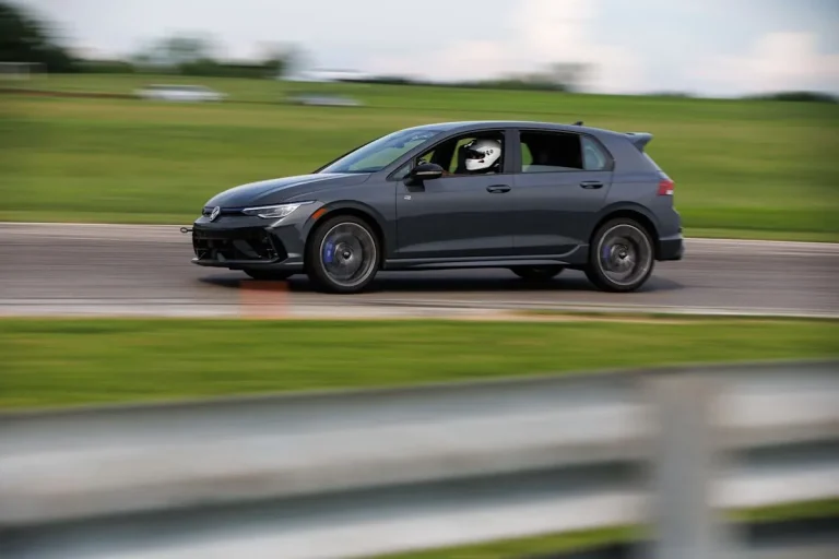 The 2026 VW Golf R parked near a racetrack showing its sleek design and forged wheels.