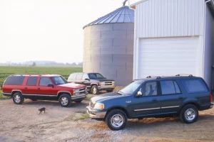 Three classic 1997 full-size American SUVs parked side-by-side during a comparison test