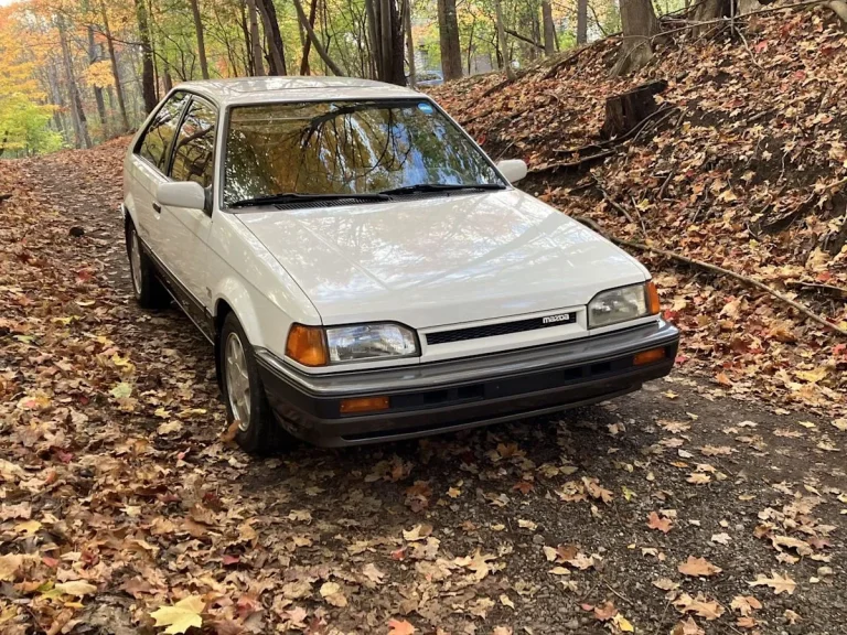 A classic white 1988 Mazda 323 GTX rally hatchback parked on a road