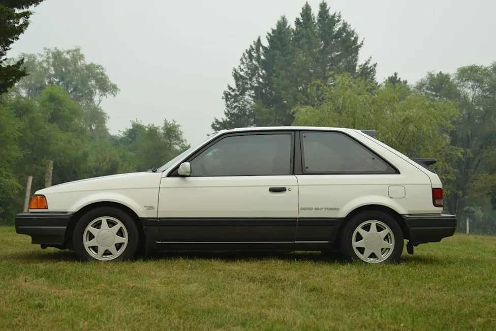 A classic white 1988 Mazda 323 GTX rally hatchback parked on a road