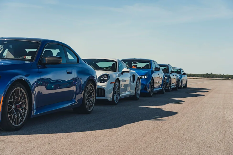 A collection of high-performance vehicles participating in a speed and braking test at Oscoda-Wurtsmith Airport.