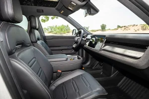 Interior cabin view of the 2026 Rivian R2 showing the dual dashboard screens and steering wheel