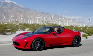 Maroon early Tesla Roadster prototype on display at an automotive gathering