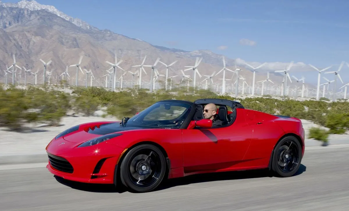 Maroon early Tesla Roadster prototype on display at an automotive gathering
