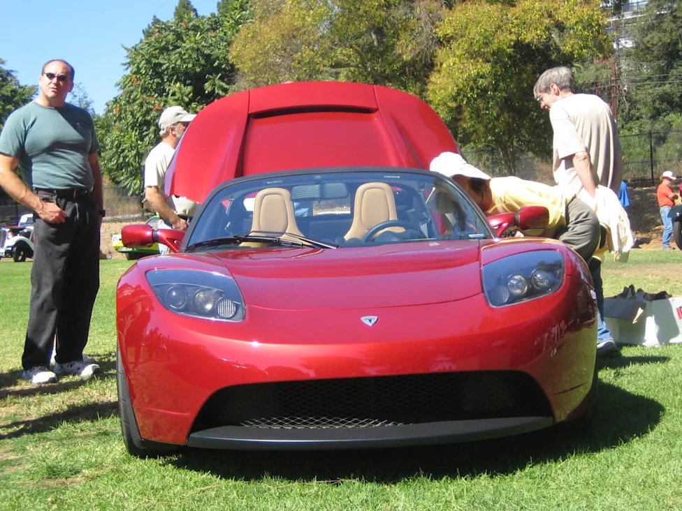 Maroon early Tesla Roadster prototype on display at an automotive gathering